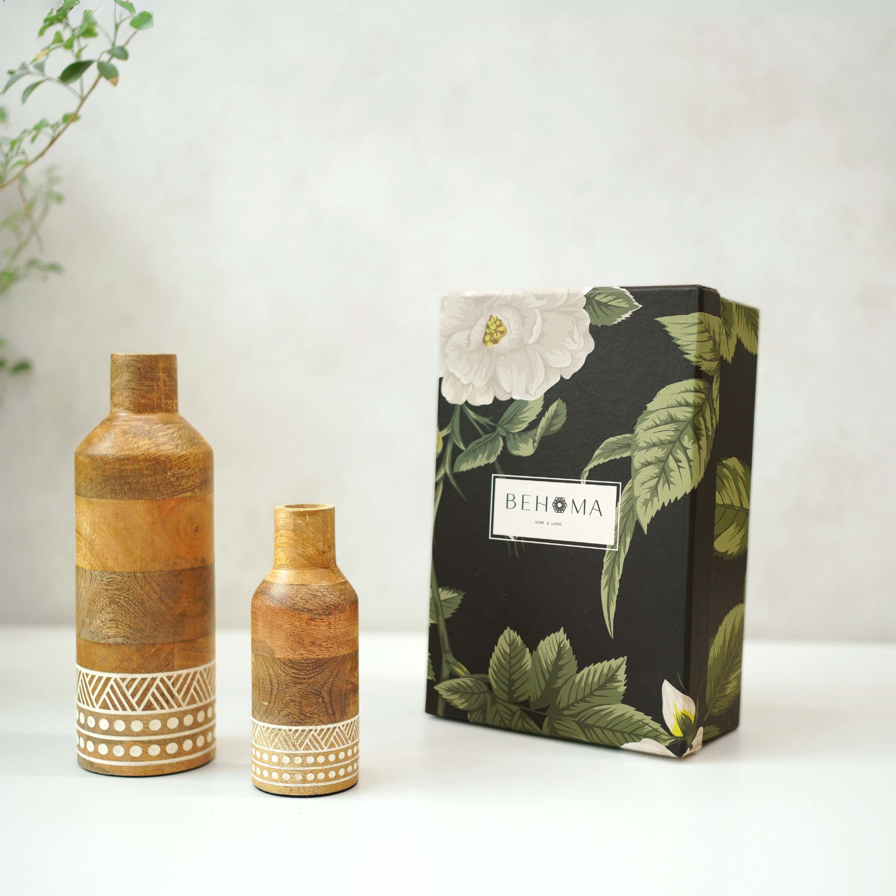 Two wooden vases with decorative patterns next to a black box with floral design and 'BEHOMA' branding.